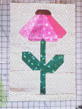 Woollypetals Echinacea Quilt Block with pink petal and green stem on polka dot background