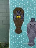 Woollypetals Manatee Migration quilt block showing brown manatee with yellow bow tie on turquoise background