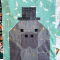 Woollypetals Manatee Migration quilt block showing pieced manatee with top hat on turquoise background