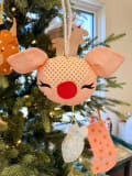 Woollypetals Reindeer Ornament with peach fabric, red nose, and glitter antlers hanging on Christmas tree