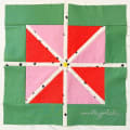 Woollypetals StarFlake quilt block in green, red, and pink fabrics