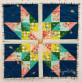 Woollypetals Starfy Mini quilt with navy, coral, green, and yellow star pattern