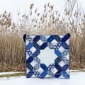 Woollypetals Floored quilt displayed in snowy landscape with dried reeds