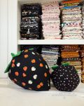 Woollypetals Strawberry Pillow stuffed projects in black fabric with orange and white strawberry prints