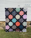 Woollypetals Floored quilt with black and colorful patchwork blocks displayed outdoors