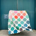 Woollypetals Floored quilt displayed with colorful star blocks and patterned fabric