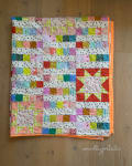 Woollypetals StarBeam quilt displayed with colorful patchwork blocks