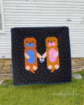 Woollypetals Don't Let Go Quilt with two otter figures holding hands on dark background