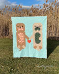 Woollypetals Don't Let Go quilt displayed outdoors with light blue background