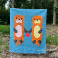 Woollypetals Don't Let Go quilt with orange otters on blue background