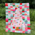 Woollypetals Oh Christmas Tree quilt displayed on grass with patchwork blocks and appliqué tree