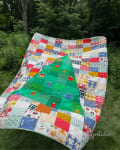 Woollypetals Oh Christmas Tree quilt with colorful patchwork border and green tree center