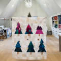 Woollypetals Enchanted Forest quilt displayed in a craft room with colorful triangle trees