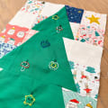 Woollypetals Enchanted Forest quilt with green fabric and festive embellishments