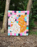Woollypetals Squirrel quilt with colorful patchwork blocks in pink, orange, turquoise, and black
