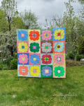 Woollypetals StarPetals Mini Quilt displayed on grass with colorful flower blocks