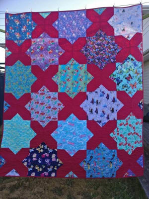 Woollypetals Floored quilt hung outdoors with red and blue patterned blocks