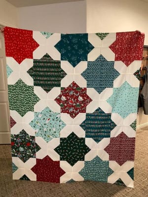 Woollypetals Floored quilt with star blocks in red, green, teal, and cream