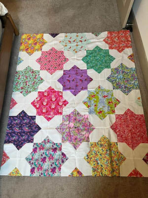 Woollypetals Floored quilt with colorful floral star blocks and cream sashing
