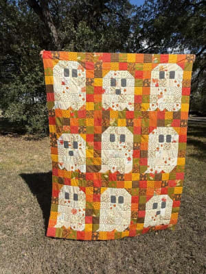 Woollypetals Ghost Party quilt with nine white ghost blocks on fall-colored patchwork background