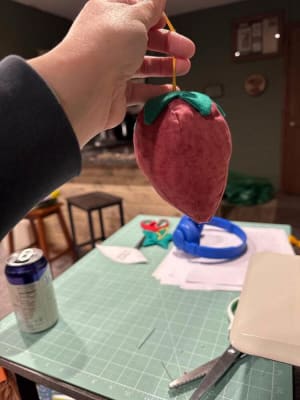 Woollypetals Strawberry Pillow held up by hand with green leaf detail