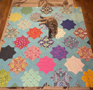 Woollypetals Floored quilt with colorful star blocks on light blue background