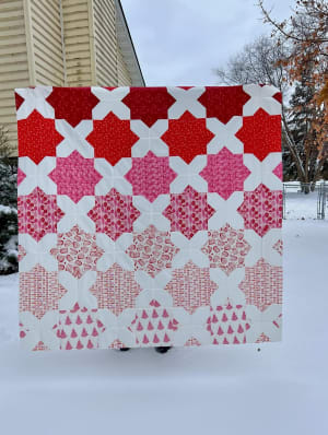 Woollypetals Floored quilt in red and pink tones displayed outdoors in snow
