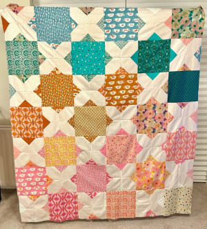 Woollypetals Floored quilt with colorful diamond star blocks in pink, teal, orange, and cream fabrics