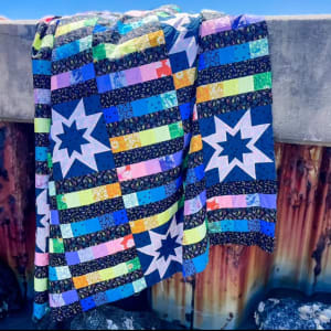 Woollypetals StarBeam Quilt with blue stars and colorful striped blocks