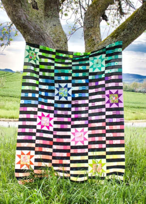Woollypetals StarBeam quilt with colorful star blocks and striped sashing