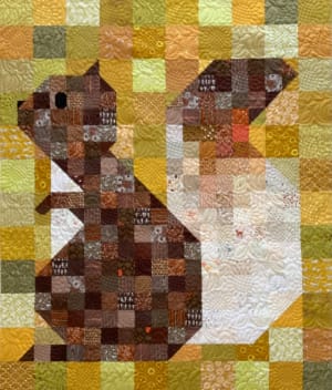 Woollypetals Squirrel quilt with brown patchwork animal on yellow and green background