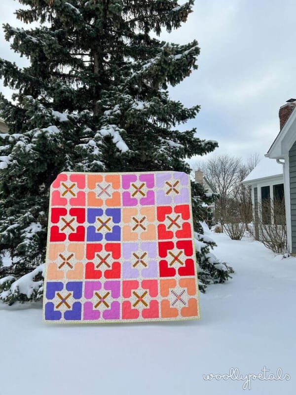 Woollypetals Hearts All Around quilt with colorful heart and X star blocks in snow