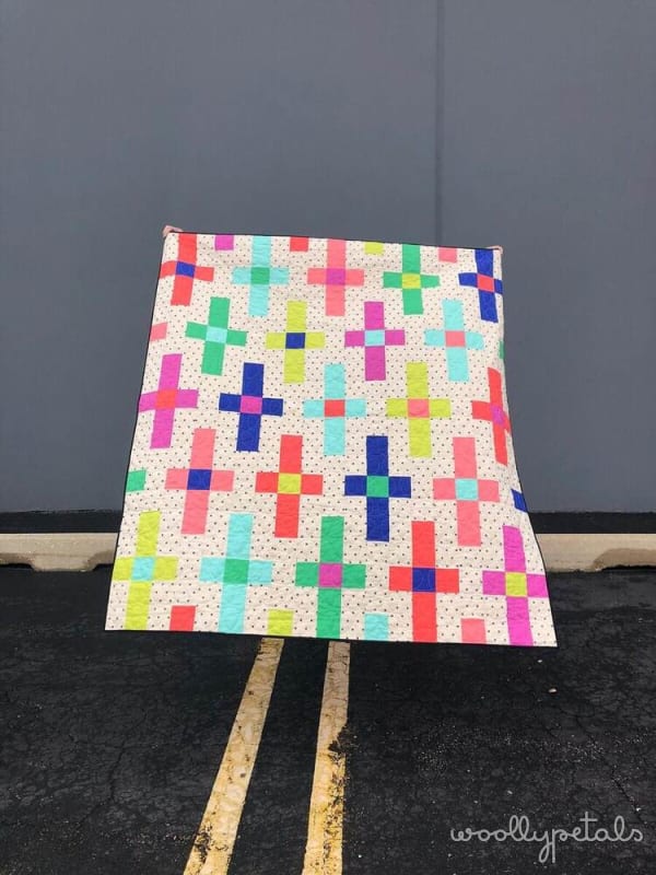 Woollypetals Moonrise quilt with colorful plus-sign blocks on cream dotted fabric
