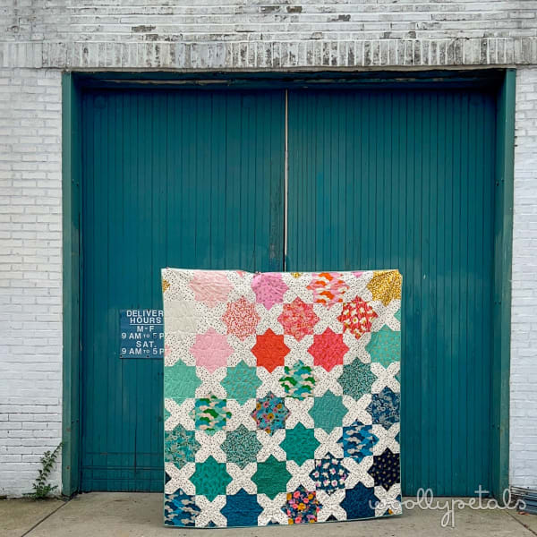 Woollypetals Floored10 quilt in multicolored star pattern displayed outdoors