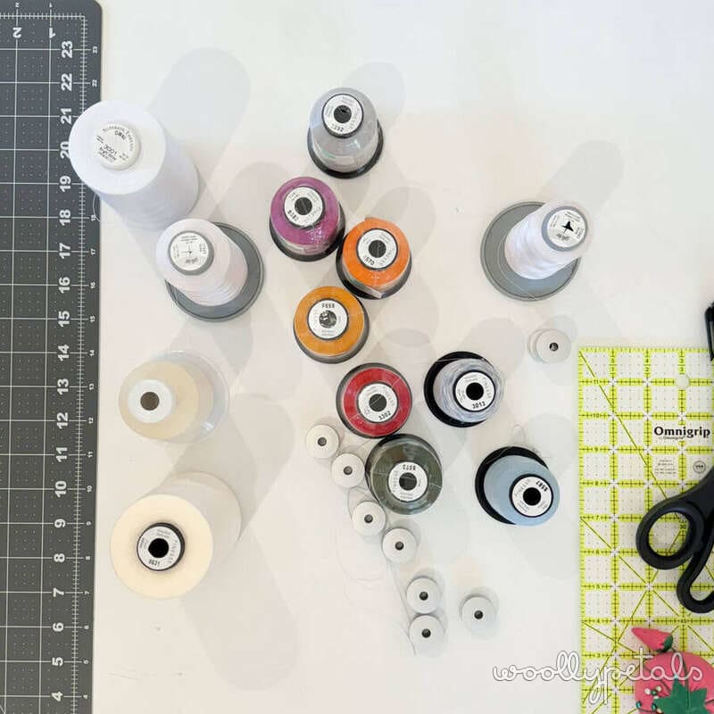 Collection of colorful thread spools arranged on cutting mat with ruler