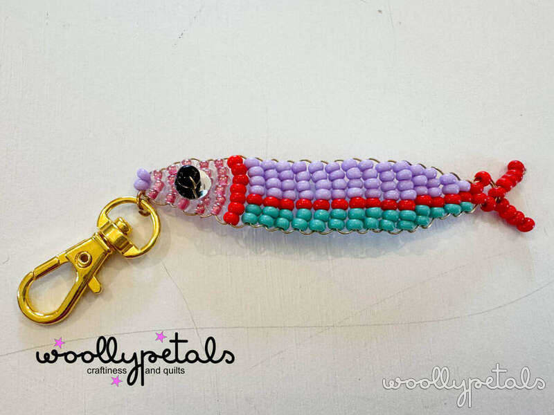 Beaded Sardine Charm with purple, red, and teal seed beads on gold clasp