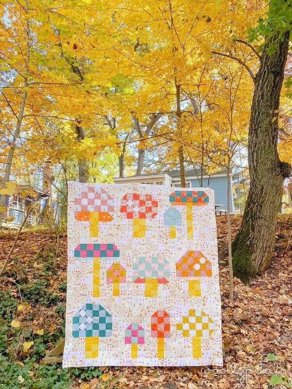 Woollypetals Capped quilt with colorful patchwork mushroom blocks displayed outdoors
