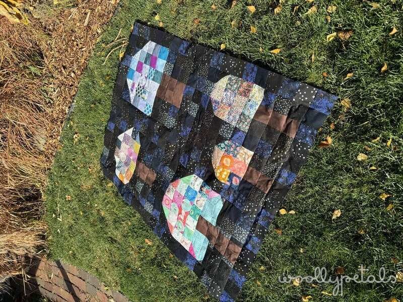Woollypetals Capped quilt with patchwork mushroom blocks displayed on grass