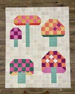 Woollypetals Capped quilt with four patchwork mushroom blocks in pink, purple, orange, and yellow