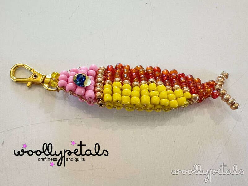 Beaded corn cob keychain with pink, red, orange, and yellow beads