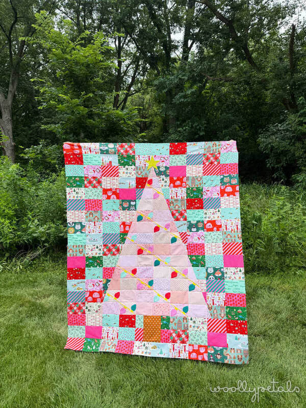 Colorful patchwork quilt with Christmas tree appliqué displayed outdoors