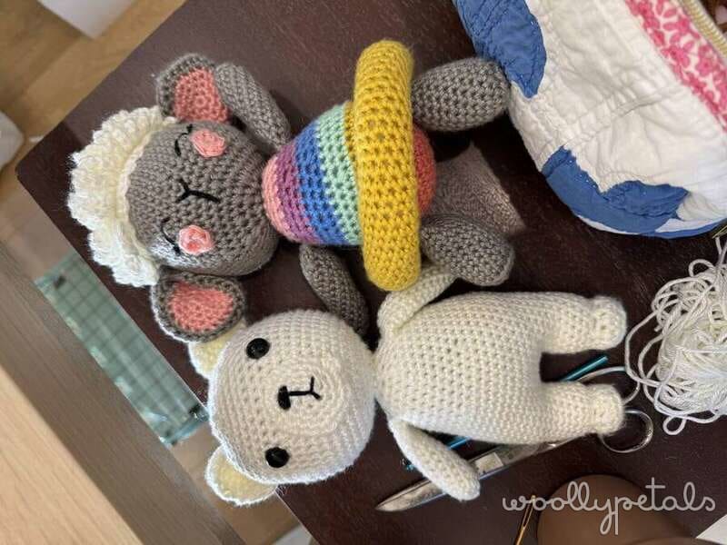 Crocheted amigurumi stuffed animals including gray cat, white bunny, and colorful rainbow striped ball