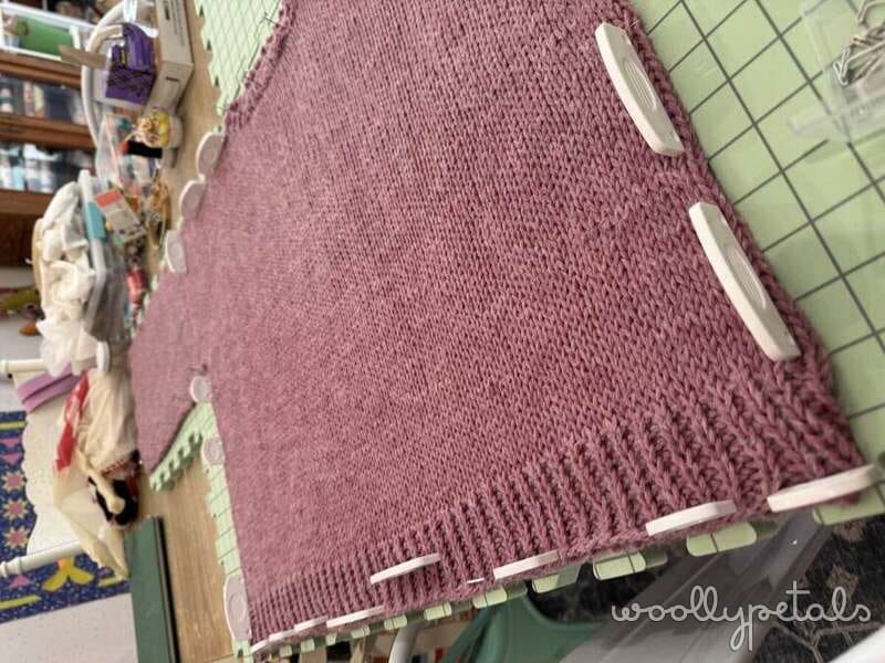 Burgundy knit blanket with white binding on blocking board