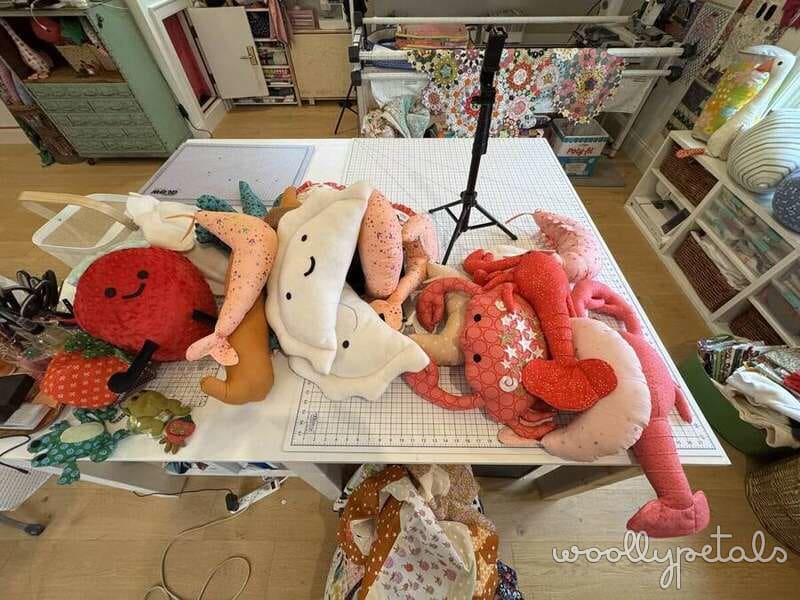 Strawberry Friends plush pillows with various fabric patterns displayed on work table