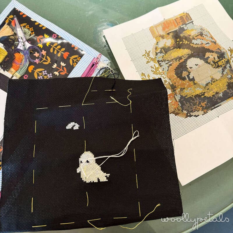 Cross stitch ghost mini quilt with black background and gold thread details