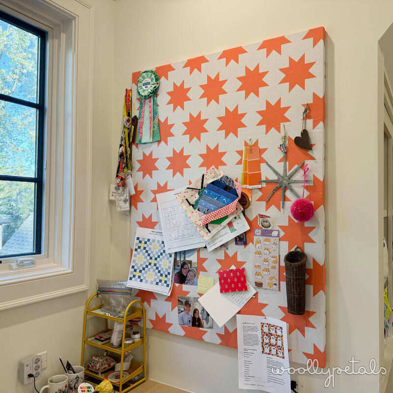 Orange and white star pattern bulletin board with hanging craft items and photos