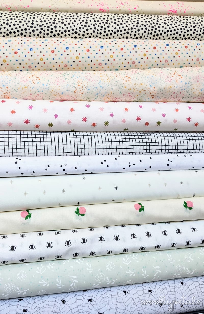 Stacked fabric rolls showing Ghost Party quilt kit with varied prints