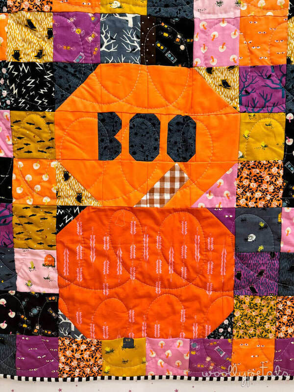 Woollypetals Ghost Party Pumpkins quilt with orange pumpkin blocks on colorful patchwork background