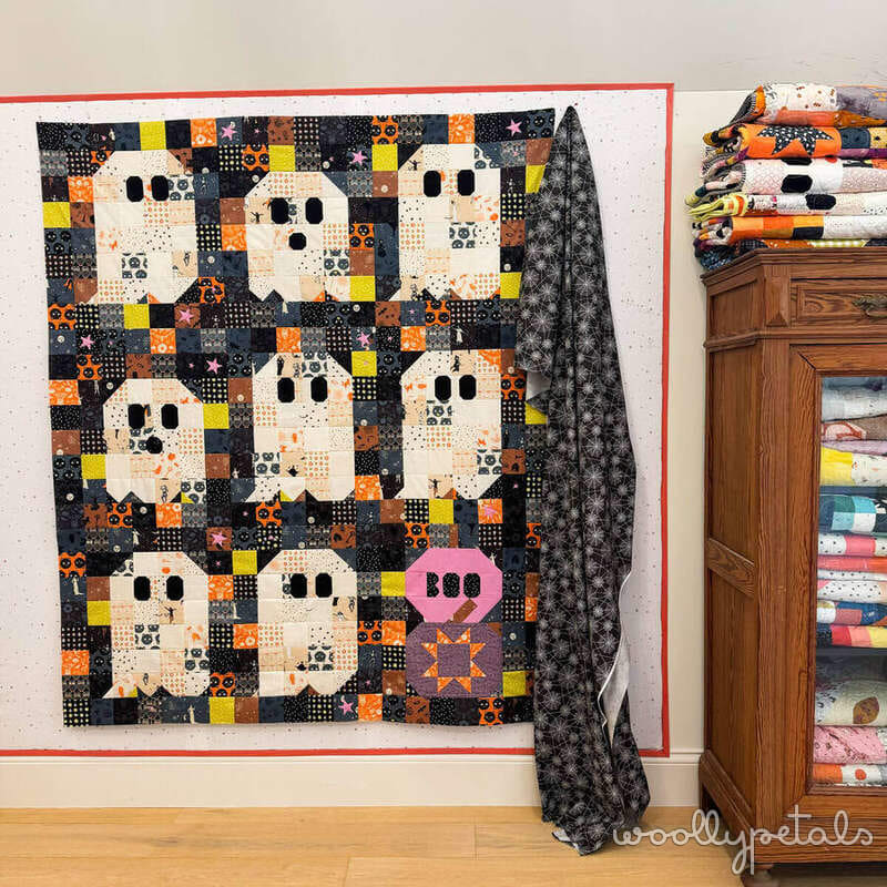 Woollypetals Ghost Party quilt displayed on wall with binding in progress