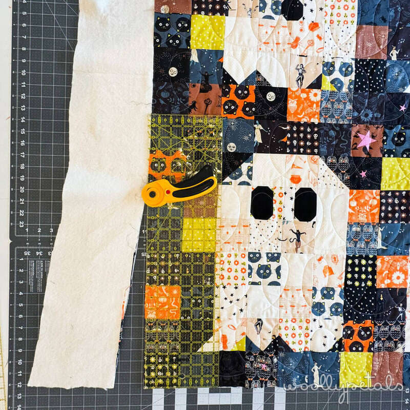 Woollypetals Ghost Party quilt top with Halloween fabrics on cutting mat